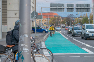 Stark befahrene Straße, Radler und PKW.